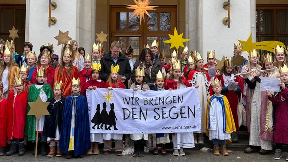 Sternsinger stehen um Schleswig-Holsteins Ministerpräsident Daniel Günther vor dem Landeshaus in Kiel und singen. | NDR / Tobias Gellert Sternsinger stehen um Schleswig-Holsteins Ministerpräsident Daniel Günther vor dem Landeshaus in Kiel und singen.