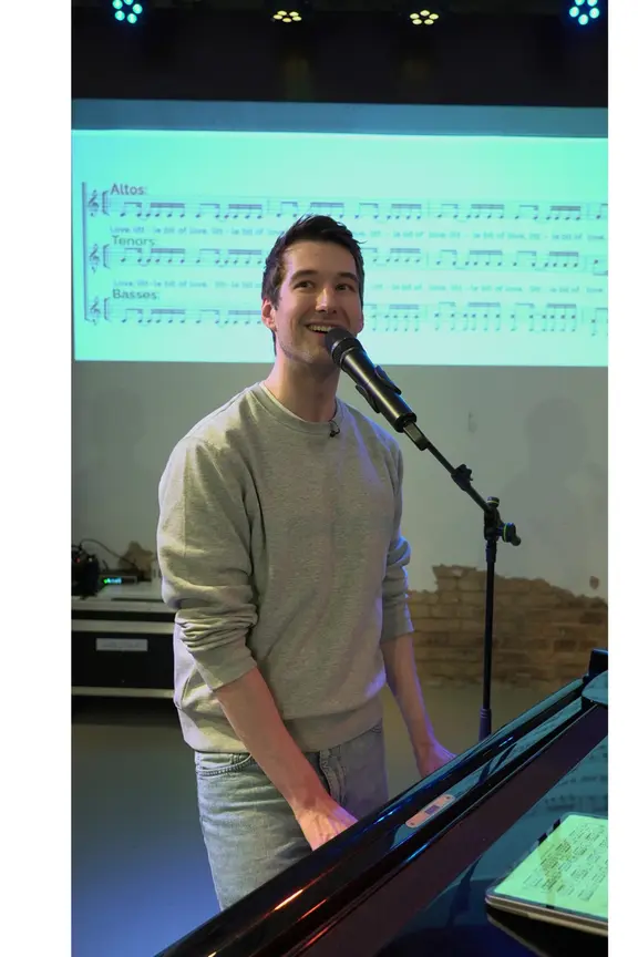 Mirko Schelske singt und spielt Klavier bei einer Chorprobe.