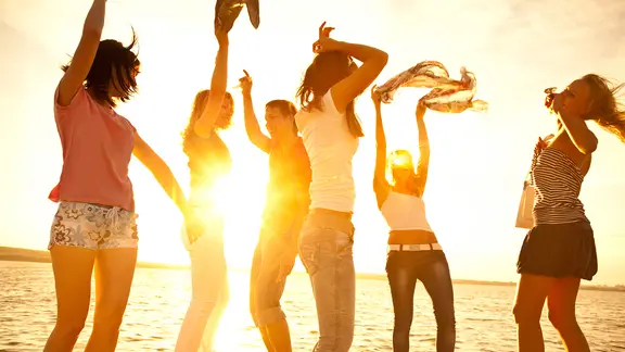 Eine Gruppe von Menschen tanzt im Sonnenuntergang.