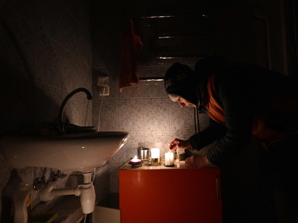 TOPSHOT - Ukrainian artist Oksana Gordiets, 67, lights candles to heat the bathroom and prevent the water in the pipes from freezing as her building experiences a power and heating outage due to Russian strikes damaging energy infrastructure, in Kyiv, on January 25, 2026, amid the Russian invasion of Ukraine. Ukrainian President Volodymyr Zelensky sought more air defence support from allies on Sunday as hundreds of buildings in Kyiv were without heating in freezing temperatures for a second day after Russian strikes. Russia has hit Ukrainian energy infrastructure throughout the nearly four-year war, but Kyiv says this winter has been the toughest, with hundreds of Russian drones and missiles overwhelming air defences during particularly fierce frosts. (Photo by Sergei GAPON / AFP)