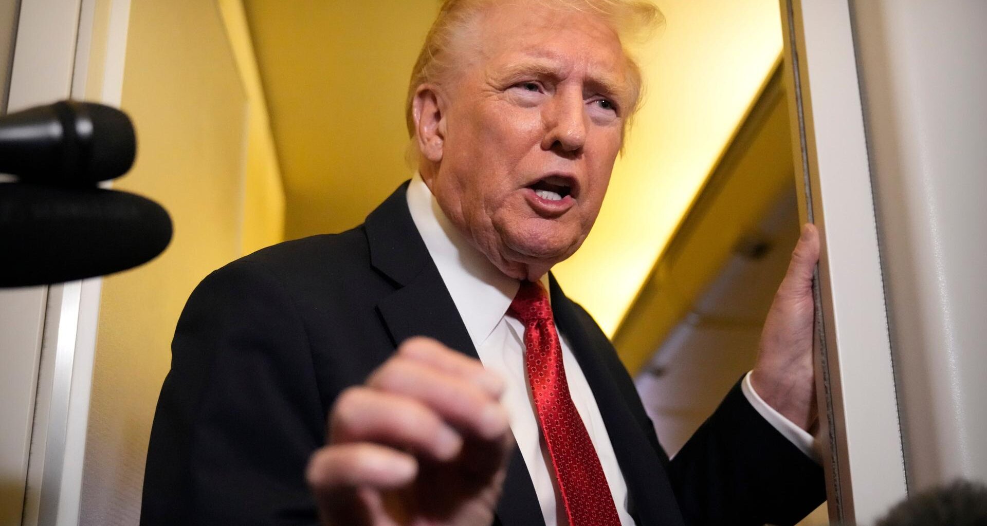 Trump steht an einem Durchgang und sagt etwas. Er gestikuliert dabei mit der rechten Hand.