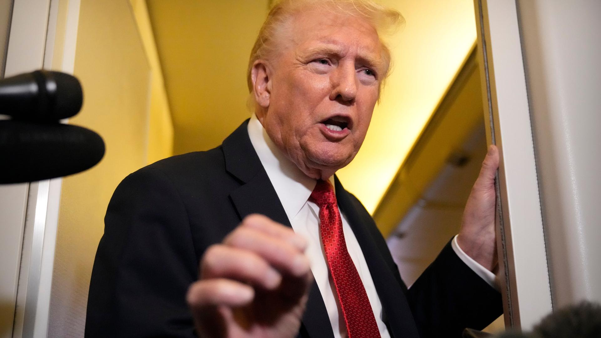 Trump steht an einem Durchgang und sagt etwas. Er gestikuliert dabei mit der rechten Hand. 