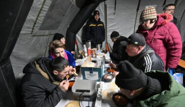 Menschen sitzen in Kiew in einem Zelt und nehmen eine warme Mahlzeit zu sich.