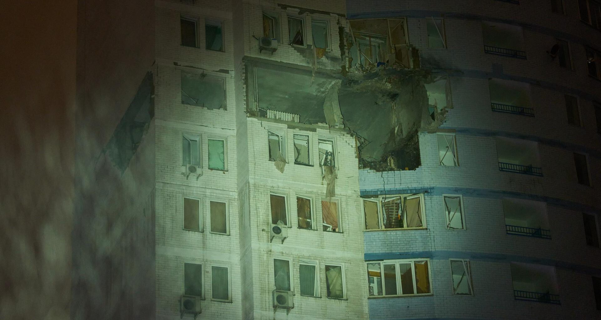Ein Wohnhaus in Kiew in der Ukraine in der Nacht. Das Haus ist angegriffen worden. Die Fenster sind kaputt. In den Wänden sind Löcher. Es schneit.