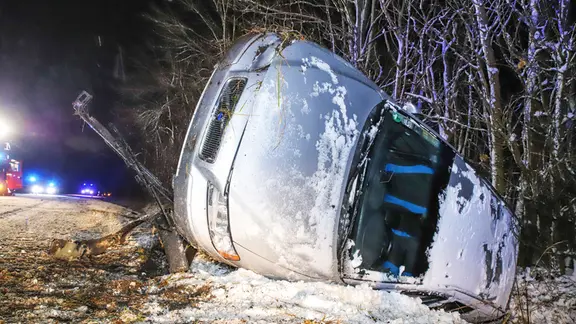 Ein Auto liegt neben der Straße auf der Seite.
