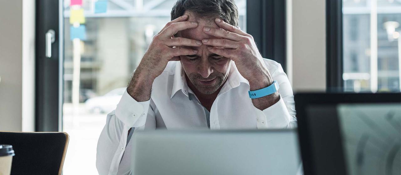 Erschöpfter Geschäftsmann in einem Büro vor einem Computer sitzend.