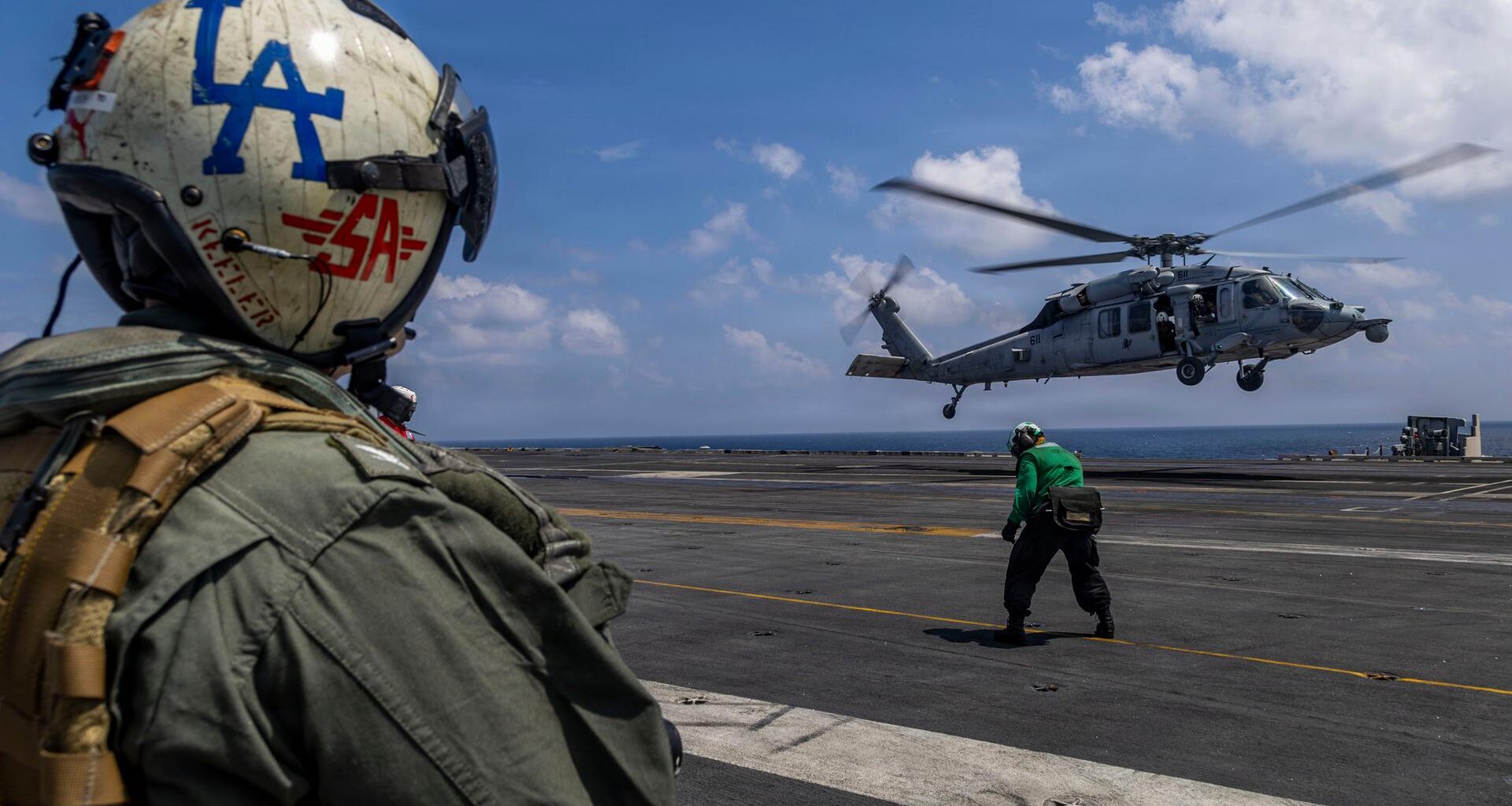 Das Foto zeigt den Kommandanten des Flugzeugträgers USS Abraham Lincoln von hinten. Im Hintergrund ist ein Hubschrauber zu sehen.