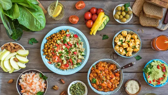 Mehrere Schalen mit veganem Essen wie Salat, Aufstrich und Nüssen auf einer rustikalen Holzfläche | colourbox, Oksana Bratanova Mehrere Schalen mit veganem Essen wie Salat, Aufstrich und Nüssen auf einer rustikalen Holzfläche