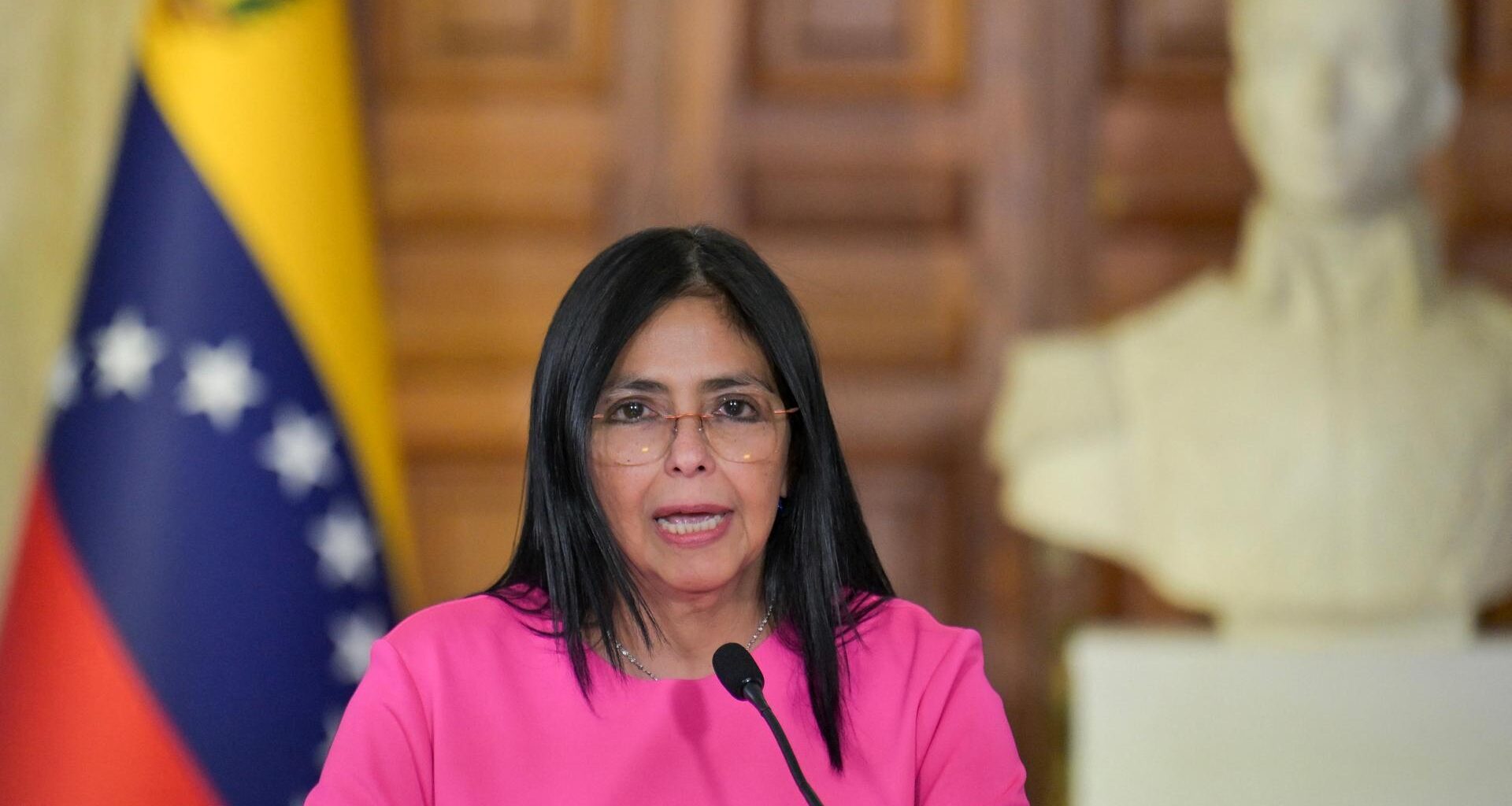 Delcy Rodriguez spricht bei einer Pressekonferenz in Caracas, im Hintergrund ist eine venezolanische Flagge zu sehen.