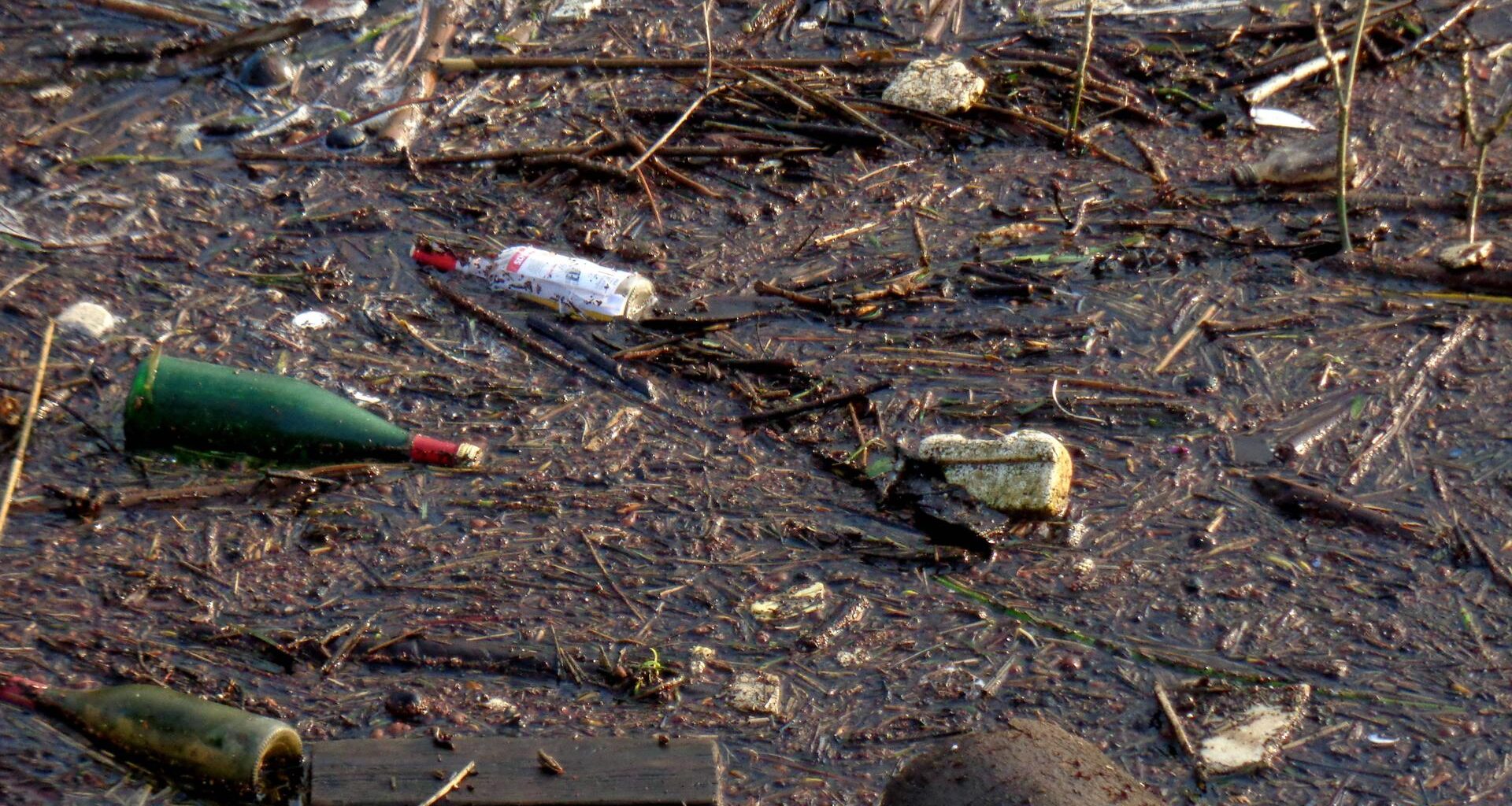 Müll an diversen Stellen im Uferbereich eines Flusses