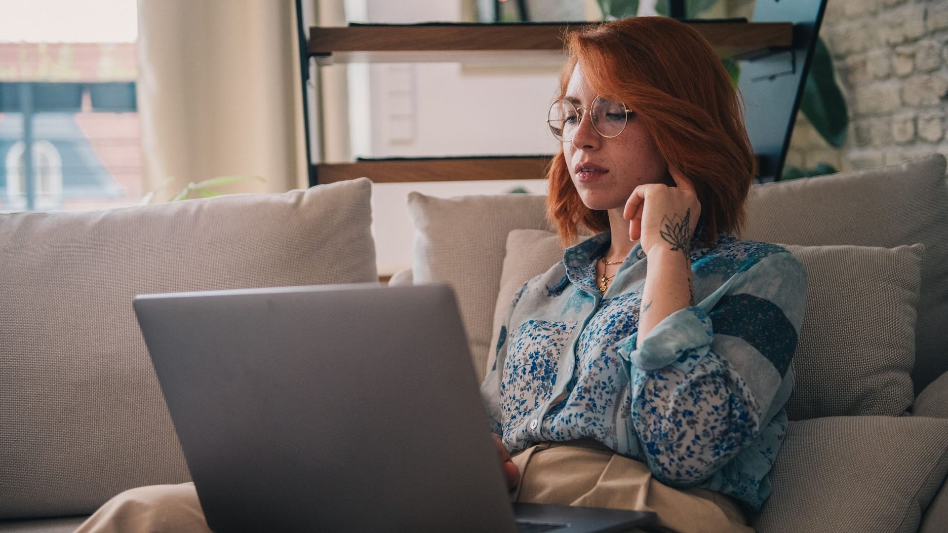 Eine Frau sitzt auf der Couch und nutzt einen Laptop Eine Frau sitzt auf der Couch und nutzt einen Laptop