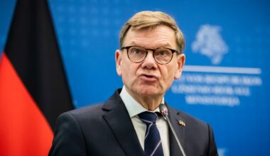 Wadephul steht vor einer blauen Wand mit der deutschen Flagge.