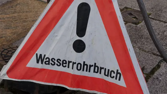 Ein Warnschild mit der Aufschrift "Wasserrohrbruch !"