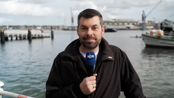 NDR Meteorologe Sebastian Wache bezeichnet das Schneesturmtief als turbulent. | NDR NDR Moderator Sebastian Wache steht an der Kieler Förde