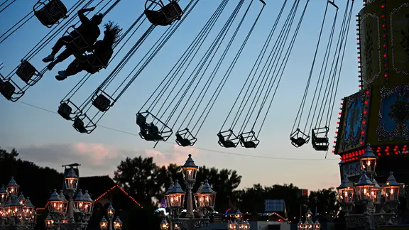 Menschen fahren auf dem Schützenfest in Hannover mit einem Kettenkarussell.