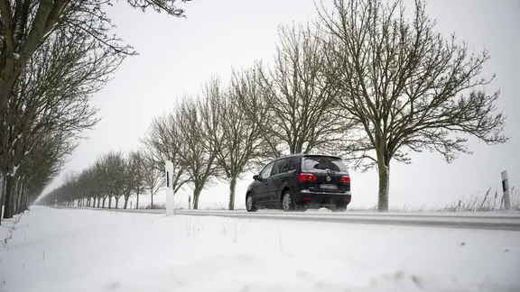 Ein Auto fährt in Leezen (Landkreis Ludwigslust-Parchim) über eine schneebedeckte Landstraße.