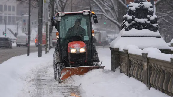 Ein Mitarbeiter des Winterdienstes fährt mit seinem Streu-und Räumfahrzeug über den Bürgersteig auf der Lombardsbrücke in der Innenstadt.