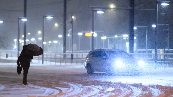 Ein Mann geht mit einem Regenschirm bei starken Schneefall zu einer Stadtbahn-Station. | picture alliance, Julian Stratenschulte Ein Mann geht mit einem Regenschirm bei starken Schneefall zu einer Stadtbahn-Station.