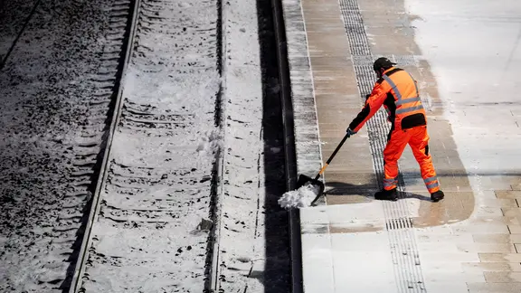 Ein Mann räumt am Hauptbahnhof Hamburg auf einem Bahnsteig Schnee.