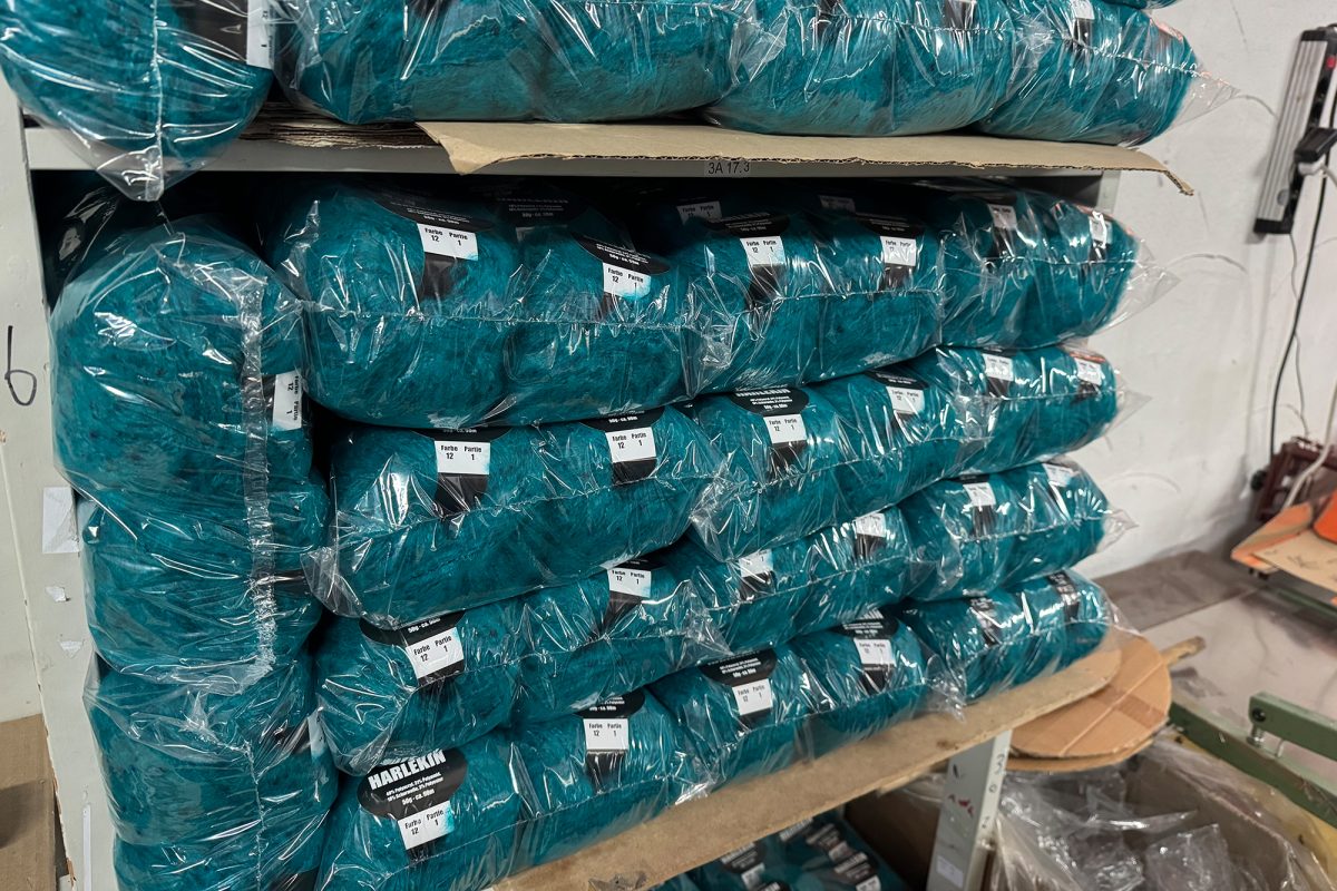 Wollknäuel liegen gestapelt im Lager