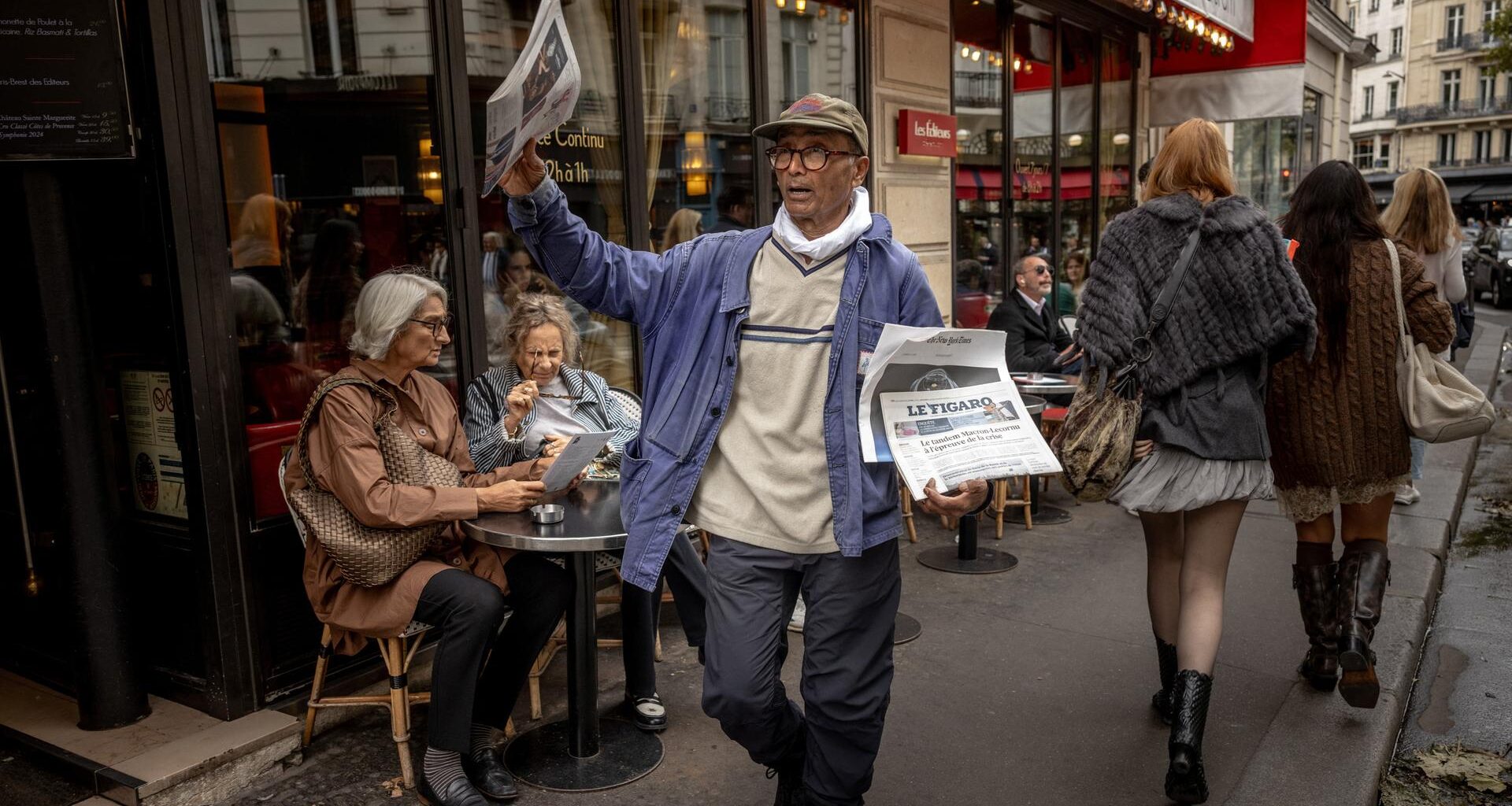 Der Zeitungsverkäufer Ali Akbar läuft durch Paris und bietet seine Ware an