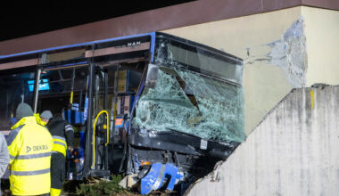 Ein schwer beschädigter Bus, der gegen eine Hausfassade geknallt ist.