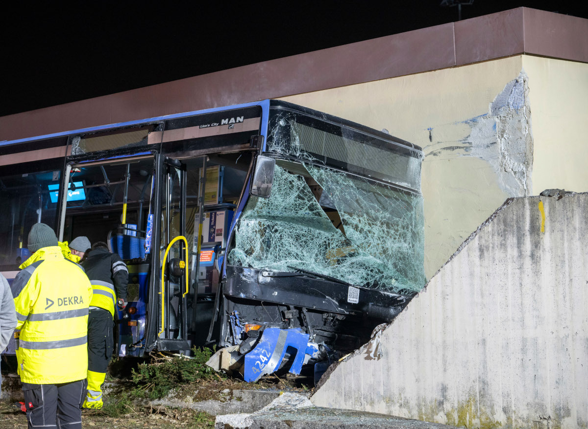 Ein schwer beschädigter Bus, der gegen eine Hausfassade geknallt ist.