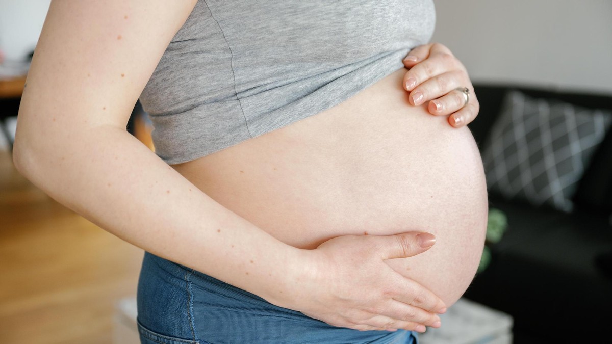 Close-up of pregnant woman touching her belly at home Close-up of pregnant woman touching her belly