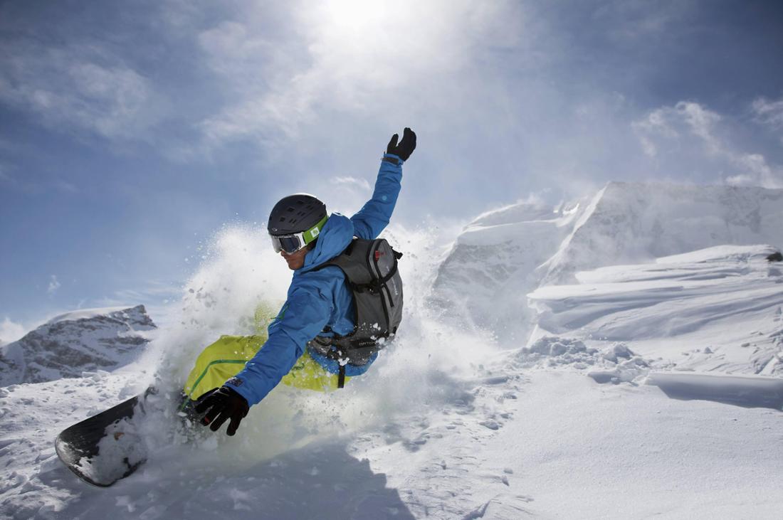 Junger Mann fährt mit seinem Snowboard bei St. Moritz durch den Schnee