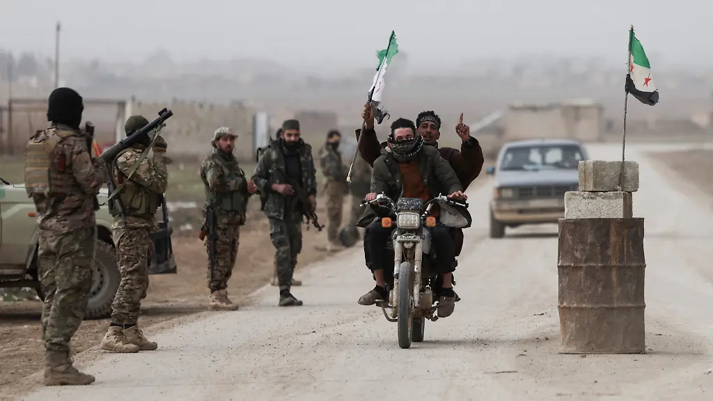 A-man-rides-a-motorcycle-and-raises-the-Syrian-flag-next-to-a-Syrian-army-checkpoint-on-the-outskirts-of-the-city-of-Al-Hasakah-Syria-February-2-2026