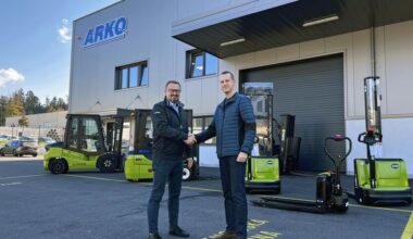 Zwei Unternehmensvertreter stehen vor dem Arko Firmengebäude und reichen sich die Hand.