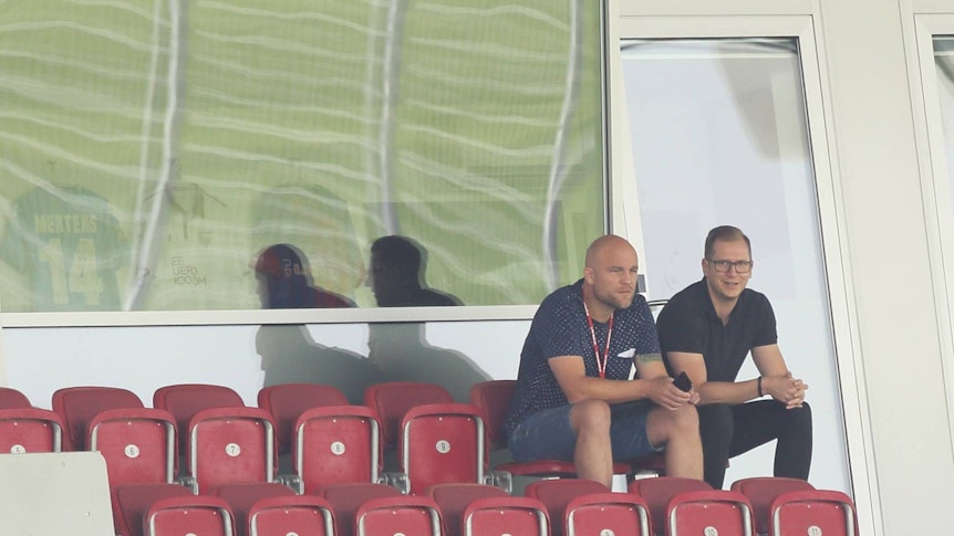 Rouven Schröder und Andre Hechelmann sitzen nebeneinander auf der Tribüne.