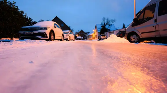 Schnee und Eis liegen auf einer nicht geräumten Straße.