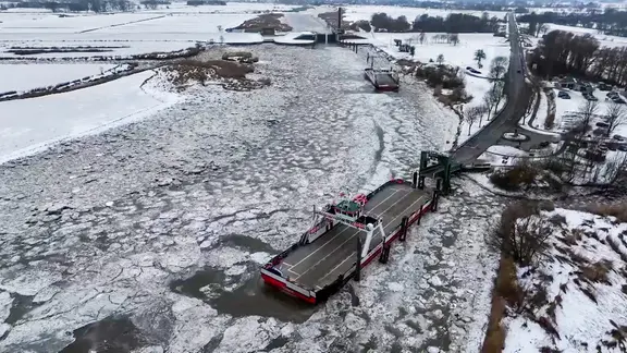 Zwei Elbfähren von Eisschollen umgeben am Anleger in Wischhafen