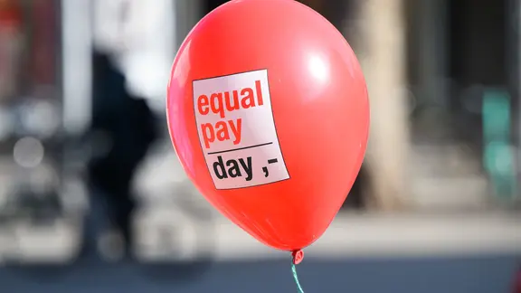 Ein Ballon mit der Aufschrift "Equal Pay Day" fliegt durch die Luft. | picture alliance/dpa | Julian Stratenschulte, Julian Stratenschulte Ein Ballon mit der Aufschrift "Equal Pay Day" fliegt durch die Luft.