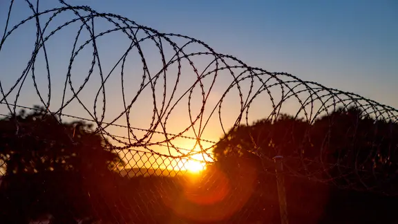 Der Stacheldraht eines Gefängnisses im Sonnenuntergang.