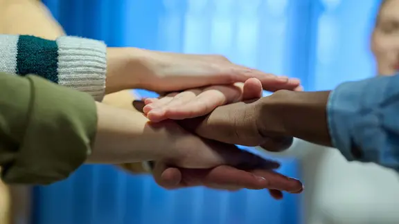 Mehrere Hände übereinander gestapelt | picture alliance / Zoonar Mehrere Hände übereinander gestapelt