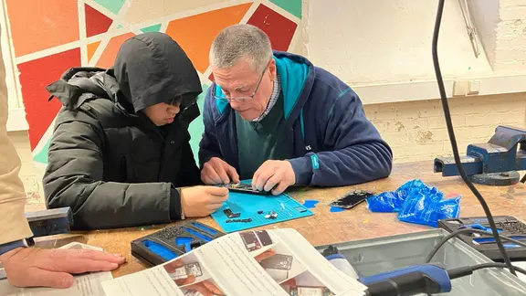 Rainer Deitmar (r.) erklärt Schüler Thien Nguyen, wie man ein Handy öffnet. | NDR. Sabine Hausherr Ein Mann erklärt einem Schüler die Technik im Handy.