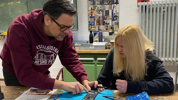 Lehrer Gunnar Müller hilft Schülerin Sarah Luderer beim Auseinanderbauen eines Handys. | NDR, Sabine Hausherr Ein Lehrer erklärt einer Schülerin die Technik im Handy.
