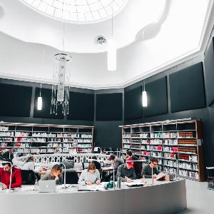 Der Blick auf Studierende die in einer Bibliothek lernen welche eine gläßerne Kuppel als Dach hat.