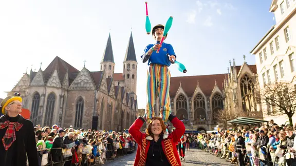 Eine mit Keulen jonglierende Karnevalistin nimmt am Karnevalsumzug «Schoduvel» teil und überquert den Altstadtmarkt. | picture alliance/dpa | Moritz Frankenberg Eine mit Keulen jonglierende Karnevalistin nimmt am Karnevalsumzug «Schoduvel» teil und überquert den Altstadtmarkt.