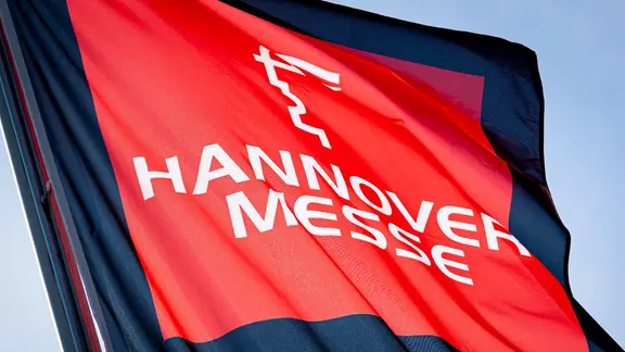 Eine Fahne zur Hannover Messe weht im Licht der Sonne auf dem Messegelände. | dpa, Moritz Frankenberg Eine Fahne zur Hannover Messe weht im Licht der Sonne auf dem Messegelände.