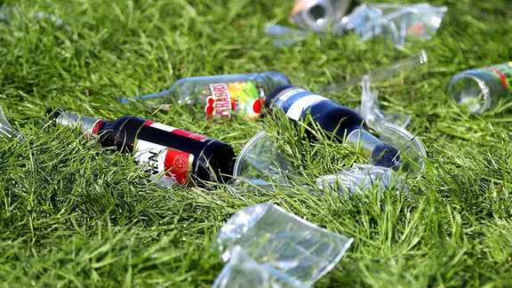 Leere Alkohol-Flaschen liegen im Rasen herum. | IMAGO / Maximilian Koch Leere Alkohol-Flaschen liegen im Rasen herum.