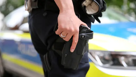 Ein Polizist hält seine Hand auf seiner geöffneter Dienstwaffe im Halfter am Gürtel. | NDR, Pavel Stoyan Ein Polizist hält seine Hand auf seiner geöffneter Dienstwaffe im Halfter am Gürtel.
