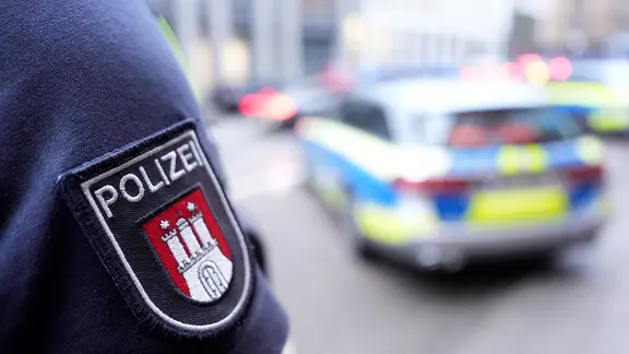 Ein Polizist steht vor einem Einsatzfahrzeug der Polizei.