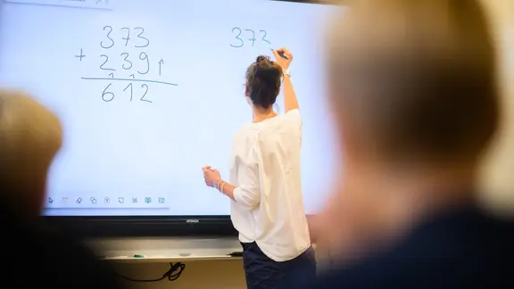 Eine Lehrerin schreibt eine Mathematikaufgabe auf eine digitale Schultafel. | picture alliance/dpa/Julian Stratenschulte, Julian Stratenschulte Eine Lehrerin schreibt eine Mathematikaufgabe auf eine digitale Schultafel.