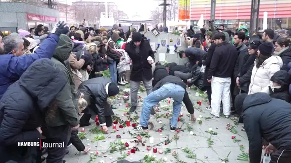 Menschen legen an der U-Bahn-Station "Wandsbek Markt" Blumen und Kerzen nieder. | Screenshot Menschen legen an der U-Bahn-Station "Wandsbek Markt" Blumen und Kerzen nieder.