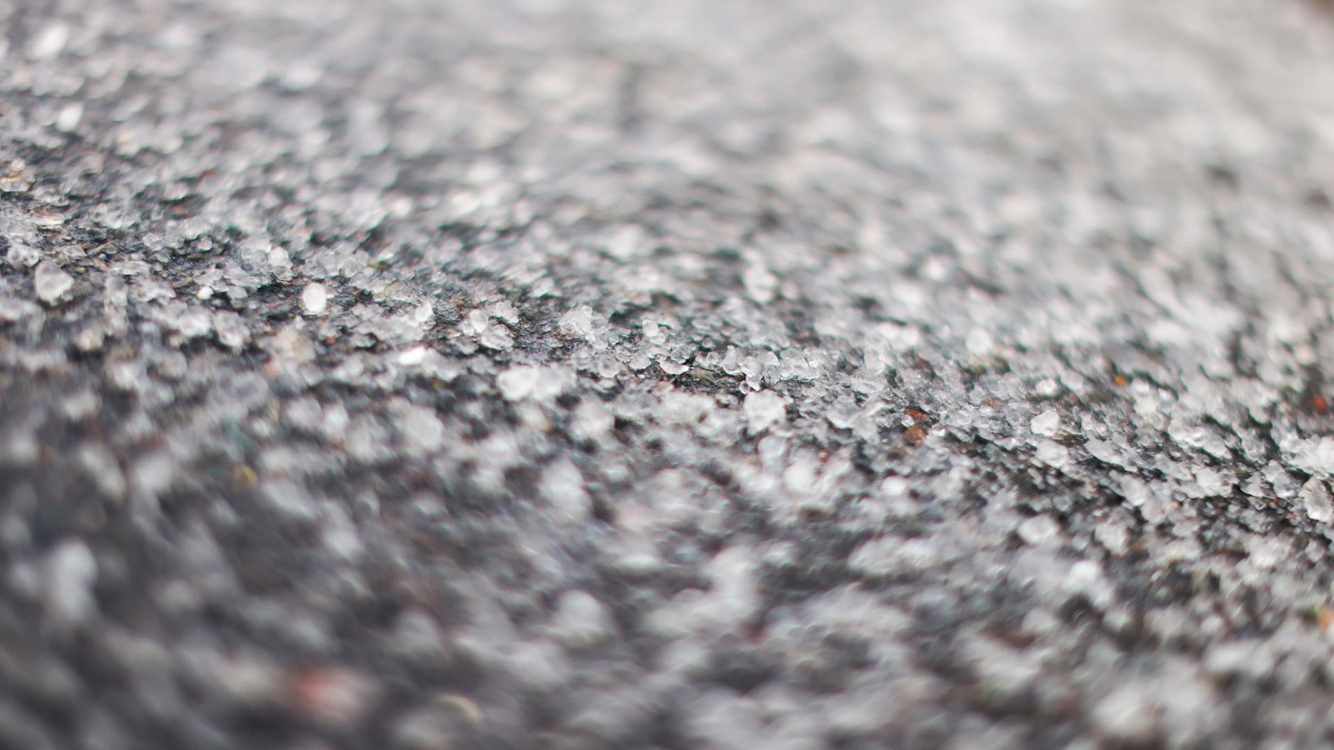 Streusalz liegt auf einer Asphaltstraße.