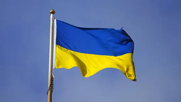Das Bild zeigt die Flagge der Ukraine wehend an einem Fahnenmast. | picture-alliance / empics, Peter Byrne Das Bild zeigt die Flagge der Ukraine wehend an einem Fahnenmast.