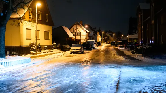 Niedersachsen, Laatzen: Der Scheinwerfer eines Autos leuchtet auf eine völlig vereiste und glatte Straße in der Region Hannover